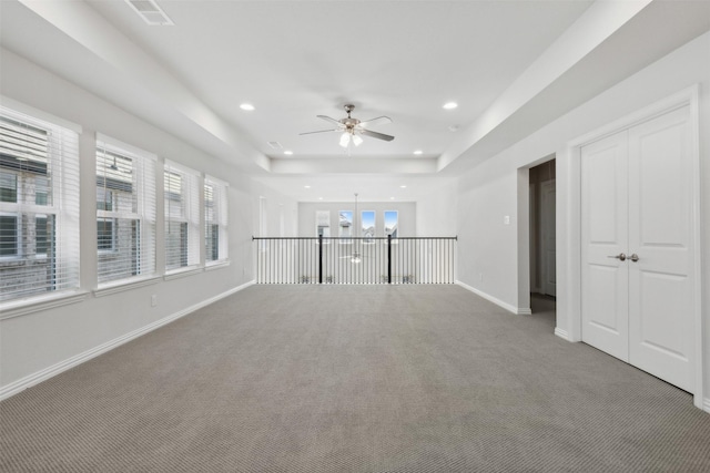 unfurnished living room with a raised ceiling, recessed lighting, carpet, and ceiling fan with notable chandelier