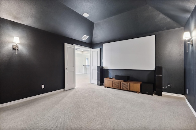 carpeted home theater room with baseboards, visible vents, and lofted ceiling