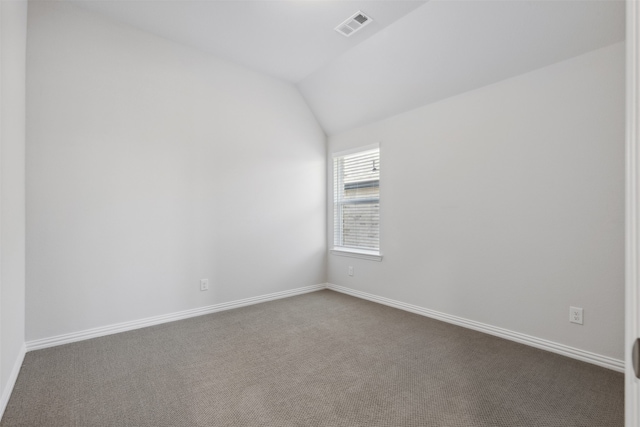 carpeted empty room featuring vaulted ceiling