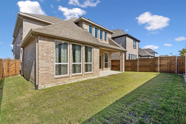rear view of house featuring a fenced backyard, a yard, and brick siding