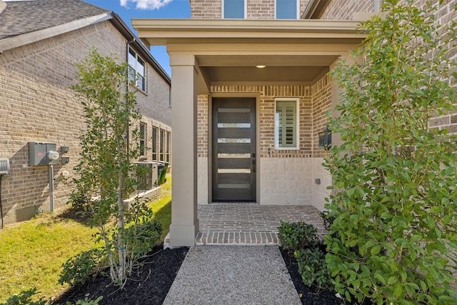 view of exterior entry featuring brick siding