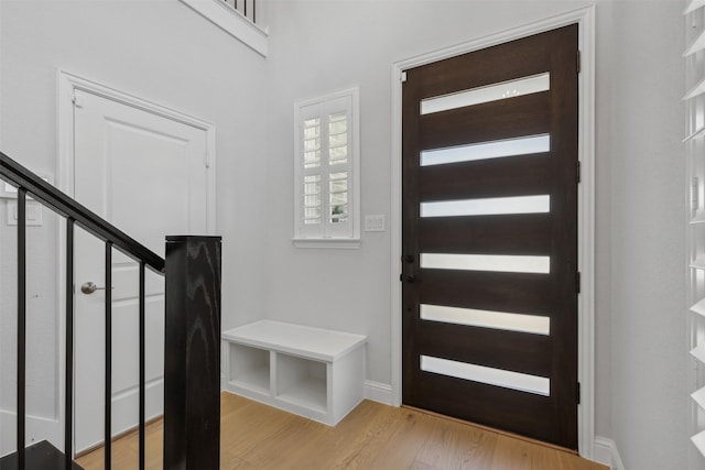 foyer with baseboards, stairway, and light wood-type flooring