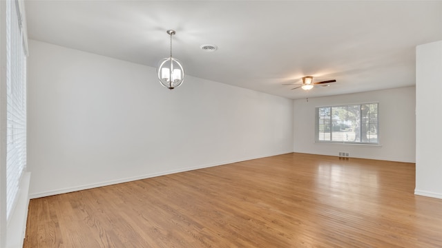 unfurnished room featuring ceiling fan with notable chandelier and light hardwood / wood-style floors