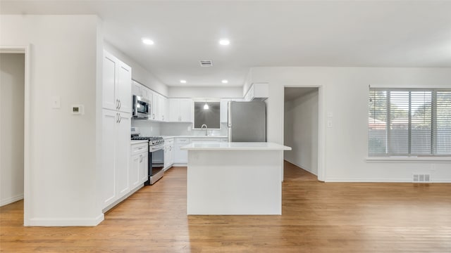 kitchen with sink, a kitchen island, white cabinetry, light hardwood / wood-style floors, and stainless steel appliances