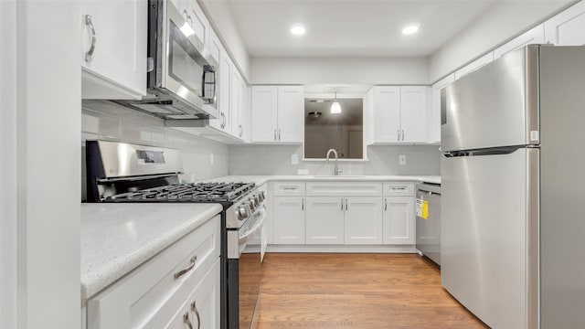 kitchen with light hardwood / wood-style floors, white cabinetry, tasteful backsplash, and stainless steel appliances