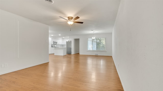 unfurnished living room featuring light hardwood / wood-style floors and ceiling fan with notable chandelier