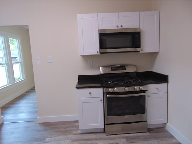 kitchen with white cabinetry, stainless steel appliances, and light wood-type flooring