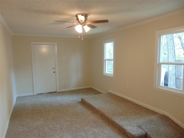 carpeted spare room featuring ornamental molding, a textured ceiling, a healthy amount of sunlight, and ceiling fan