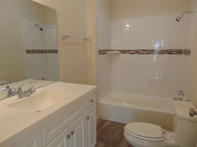 full bathroom with toilet, tiled shower / bath, hardwood / wood-style flooring, and vanity