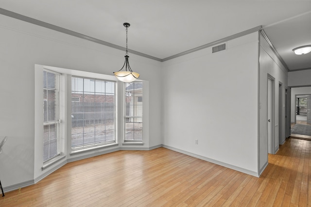 unfurnished dining area with crown molding and light wood-type flooring