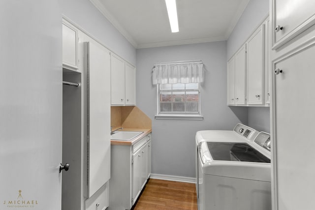 washroom with crown molding, independent washer and dryer, light wood-type flooring, and cabinets