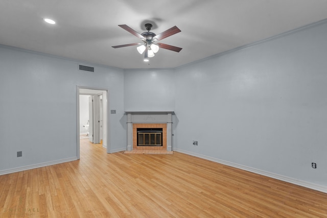 unfurnished living room featuring ceiling fan, crown molding, light hardwood / wood-style flooring, and a tile fireplace