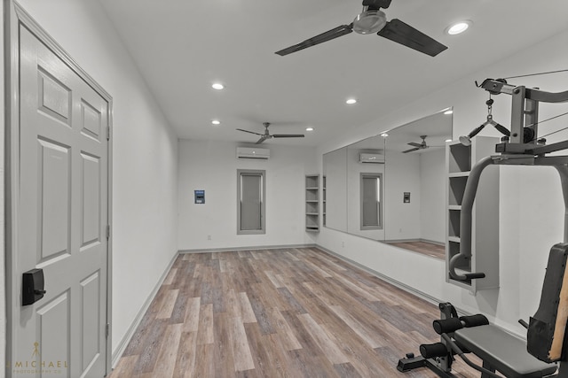 exercise room with an AC wall unit, elevator, and light wood-type flooring