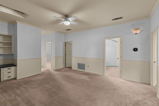 unfurnished bedroom featuring crown molding, light colored carpet, wooden walls, and ceiling fan