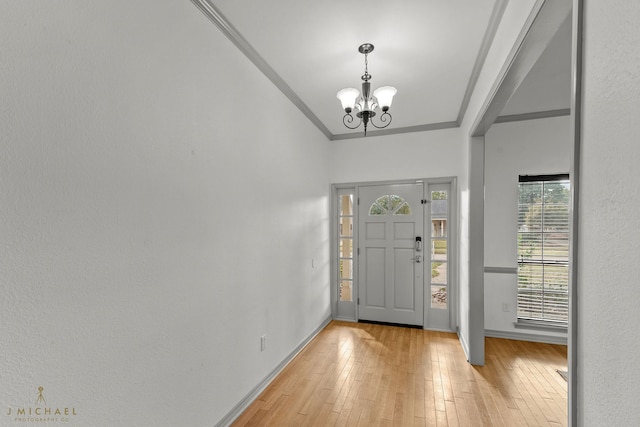 foyer entrance featuring ornamental molding, light hardwood / wood-style flooring, and a notable chandelier