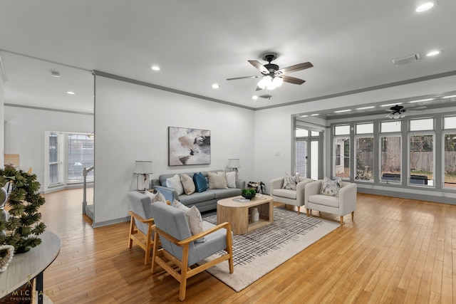 living room with light hardwood / wood-style floors, ornamental molding, and ceiling fan