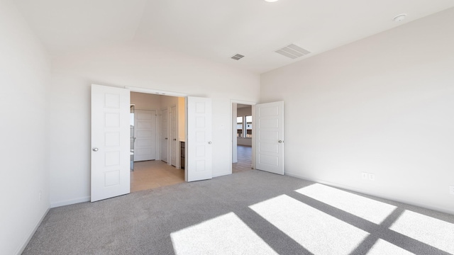 unfurnished bedroom featuring lofted ceiling and light colored carpet