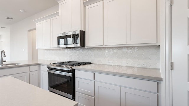 kitchen featuring white cabinets, appliances with stainless steel finishes, sink, and decorative backsplash