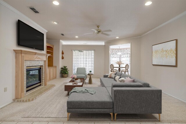 unfurnished living room featuring ceiling fan, crown molding, a brick fireplace, and light colored carpet