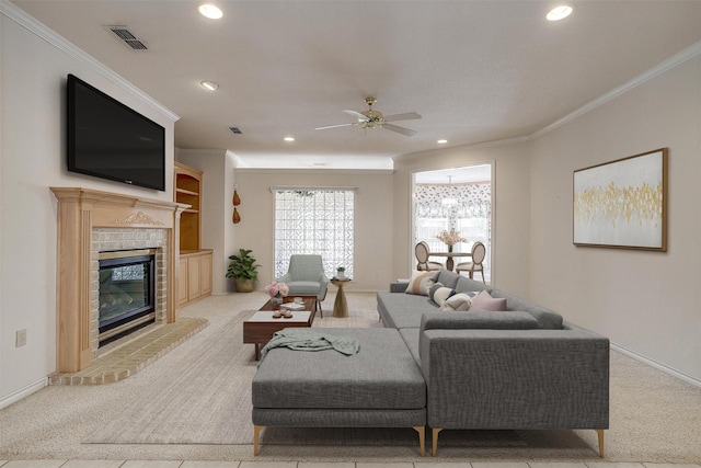 living room with crown molding, light colored carpet, ceiling fan, and a fireplace