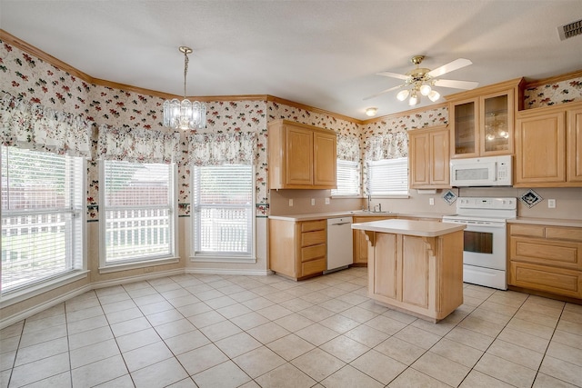 kitchen featuring a kitchen island, a healthy amount of sunlight, hanging light fixtures, and white appliances