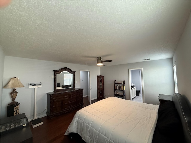 bedroom with a textured ceiling, ensuite bath, ceiling fan, and dark wood-type flooring