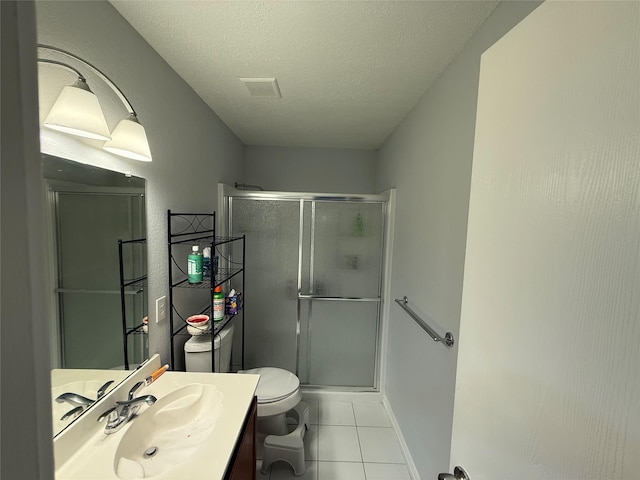 bathroom with tile patterned floors, a textured ceiling, toilet, vanity, and a shower with shower door