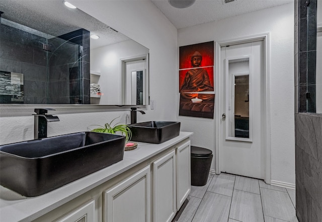 bathroom featuring walk in shower, vanity, a textured ceiling, and toilet