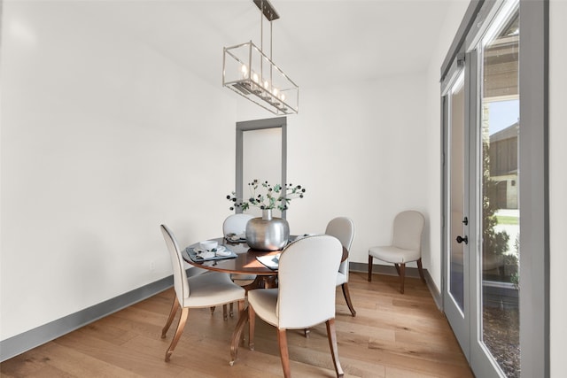 dining space with light hardwood / wood-style floors and a notable chandelier