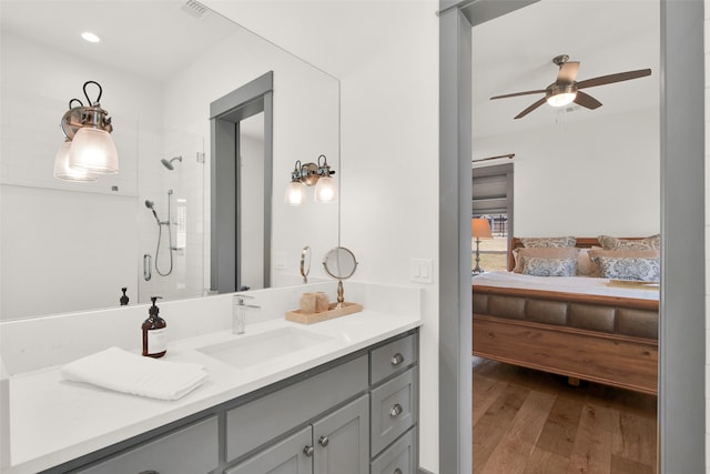 bathroom with vanity, ceiling fan, wood-type flooring, and tiled shower