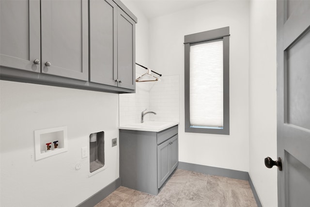 laundry area featuring cabinets, hookup for an electric dryer, sink, and a wealth of natural light