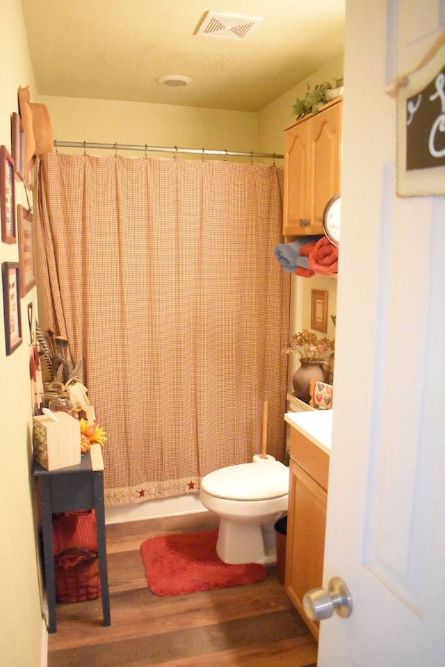 bathroom featuring vanity, toilet, hardwood / wood-style flooring, and curtained shower