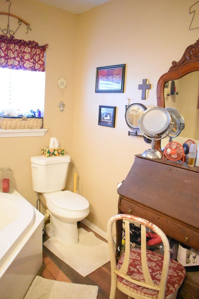 bathroom featuring a tub to relax in, hardwood / wood-style floors, and toilet