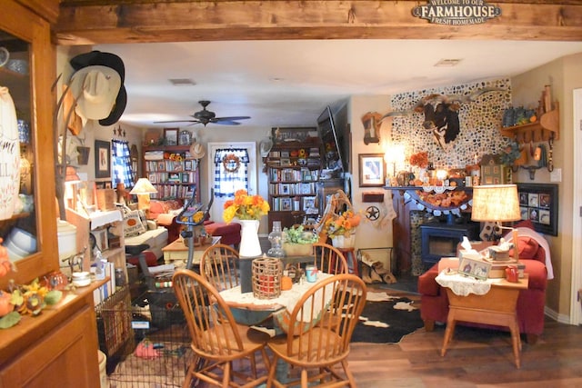 dining space with ceiling fan, beamed ceiling, a fireplace, and hardwood / wood-style floors