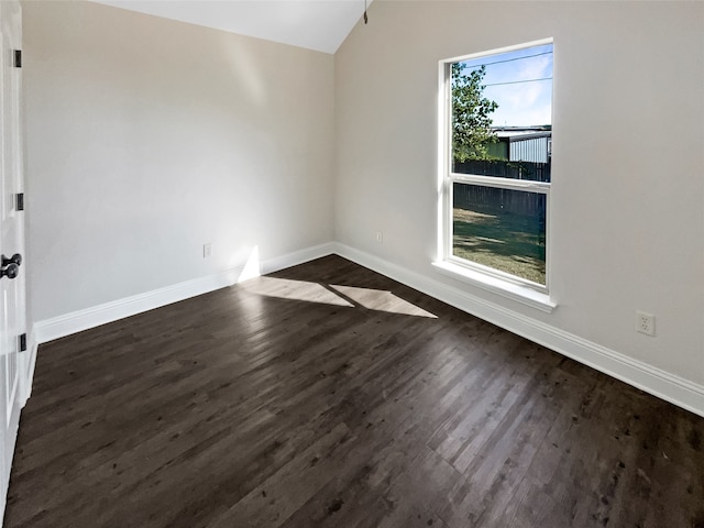 spare room featuring dark wood-type flooring and vaulted ceiling