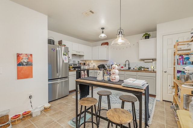 kitchen with decorative backsplash, sink, pendant lighting, white cabinetry, and appliances with stainless steel finishes