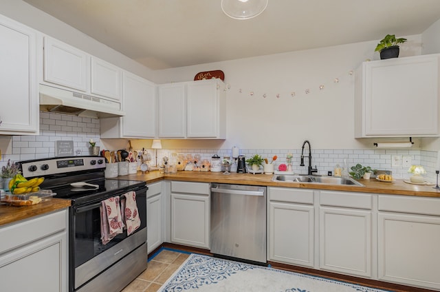 kitchen with butcher block counters, stainless steel appliances, backsplash, sink, and white cabinets