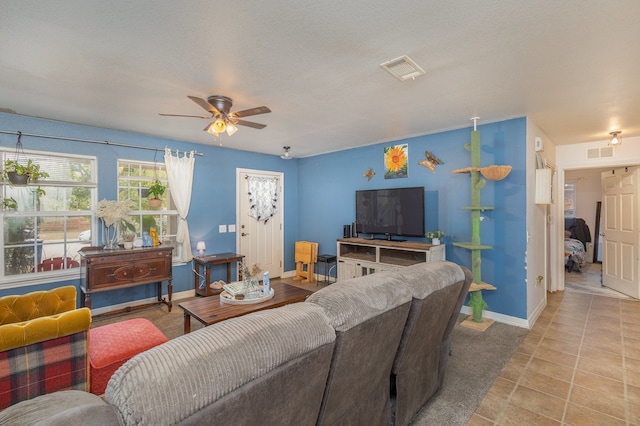 living room featuring ceiling fan, a textured ceiling, and light tile patterned floors