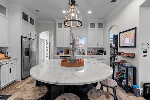 kitchen featuring a kitchen island, hanging light fixtures, crown molding, stainless steel fridge with ice dispenser, and white cabinets