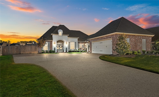 french provincial home with a garage and a lawn