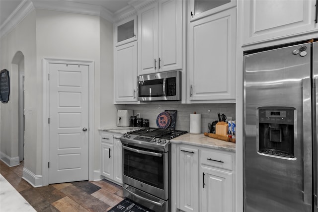 kitchen with white cabinets, light stone countertops, stainless steel appliances, and tasteful backsplash