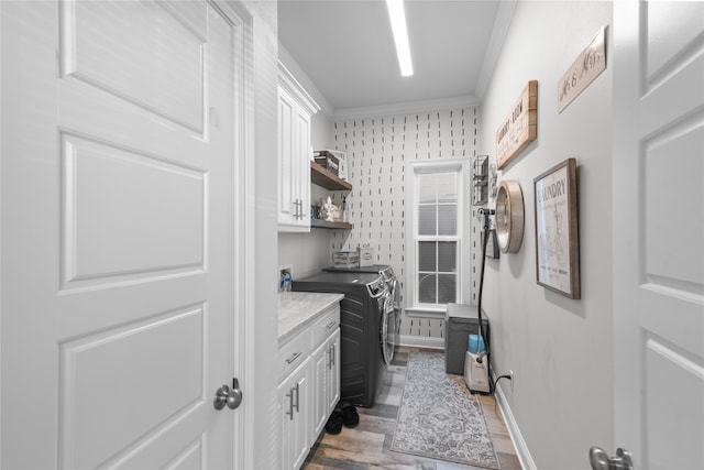 laundry area featuring dark hardwood / wood-style flooring, ornamental molding, washer and dryer, and cabinets