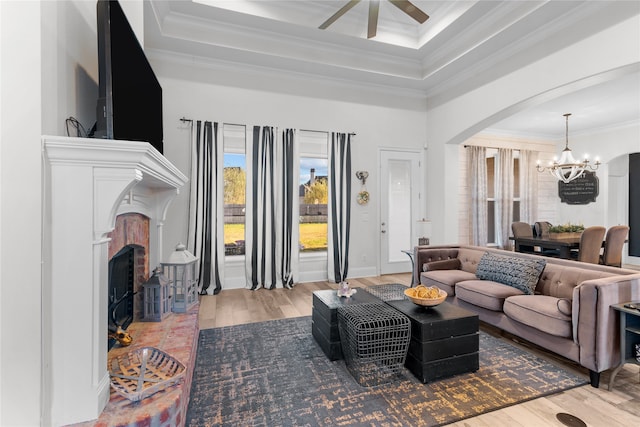 living room featuring crown molding, hardwood / wood-style flooring, a tray ceiling, and ceiling fan with notable chandelier