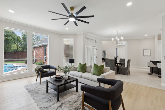 living room with ornamental molding, ceiling fan with notable chandelier, and light wood-type flooring