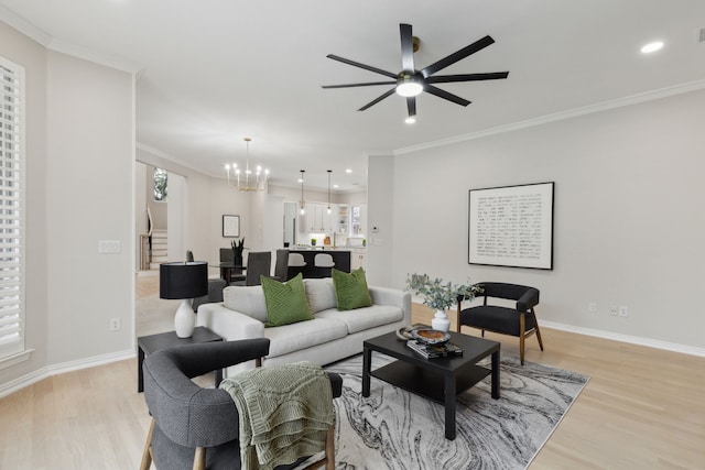 living room featuring ornamental molding, light wood-type flooring, and ceiling fan with notable chandelier