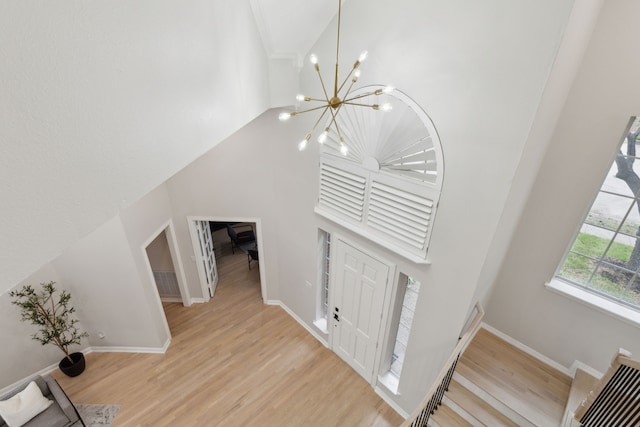 stairway with a high ceiling, a chandelier, and hardwood / wood-style floors