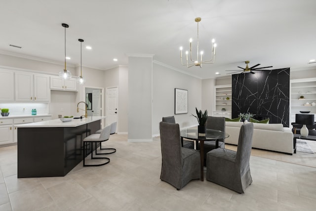 dining room featuring sink, crown molding, ceiling fan with notable chandelier, and built in features