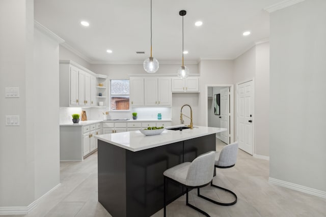 kitchen with backsplash, a center island with sink, sink, crown molding, and white cabinets