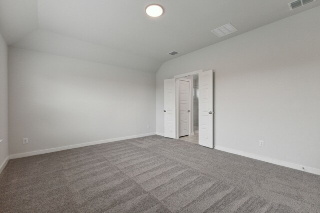 carpeted spare room with vaulted ceiling