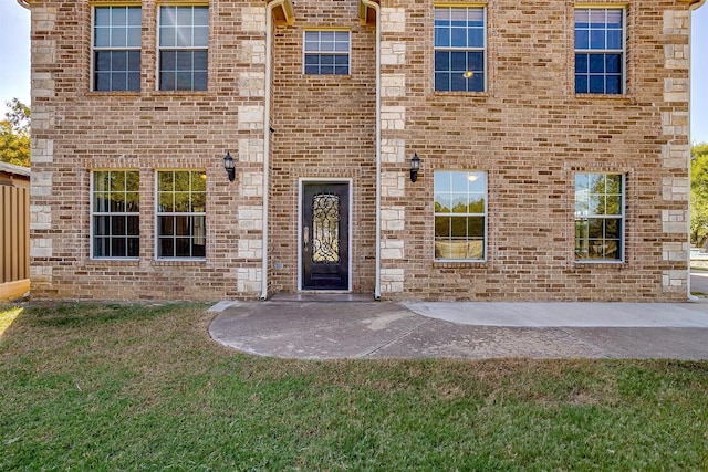 entrance to property featuring a yard and a patio